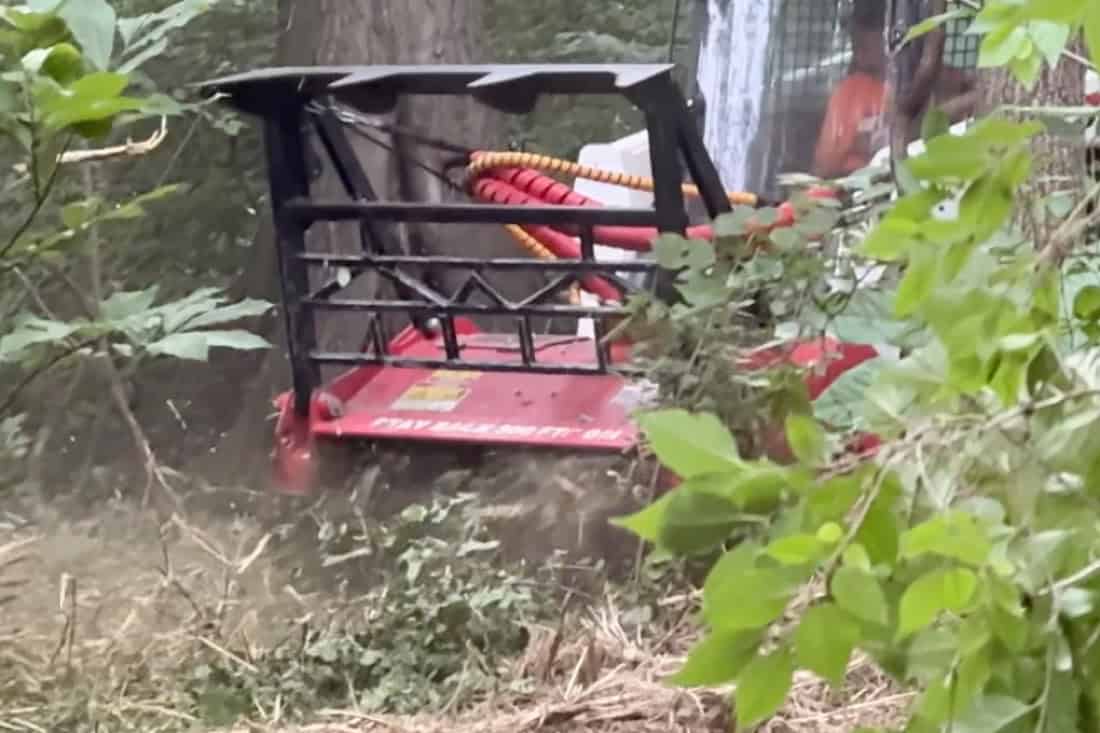 Forestry mulcher head on a skid steer grinding brush and saplings during residential land clearing near Tulsa, Oklahoma