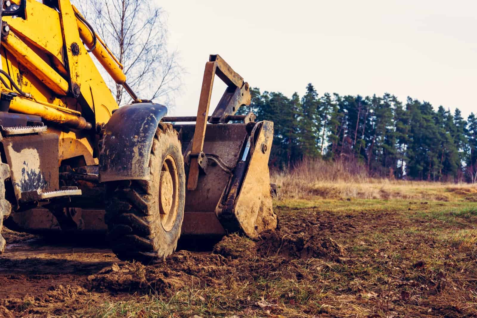 Front loader grading cleared ground at the edge of a treeline on a property near Tulsa, Oklahoma