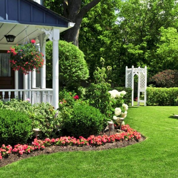 Landscape installation featuring a pergola surrounded by colorful flower bed designs