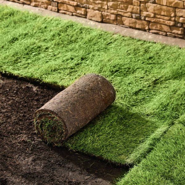 Professional landscaper unrolling sod during a residential lawn installation project