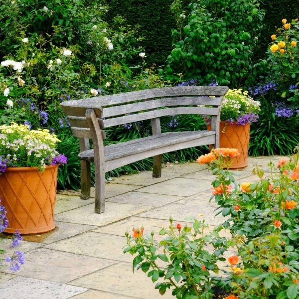 Peaceful landscape design with garden bench, potted plants, and manicured lawn