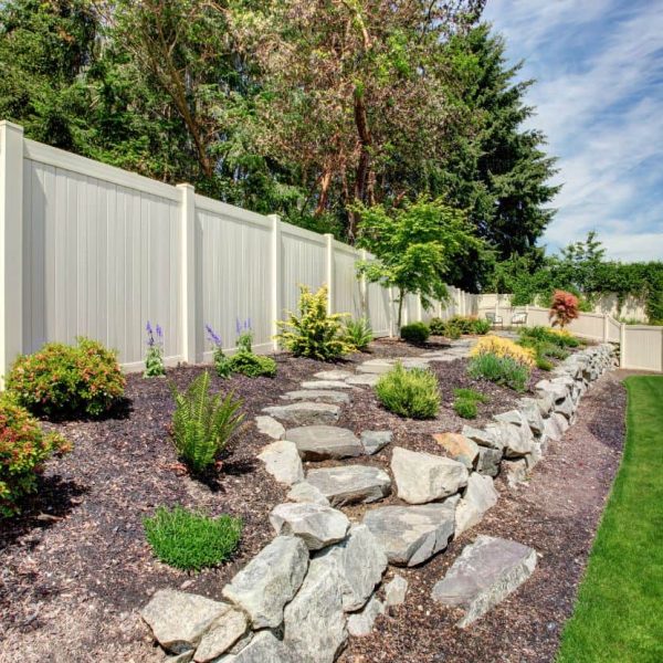Layered landscape installation with stone retaining wall and mixed garden plantings
