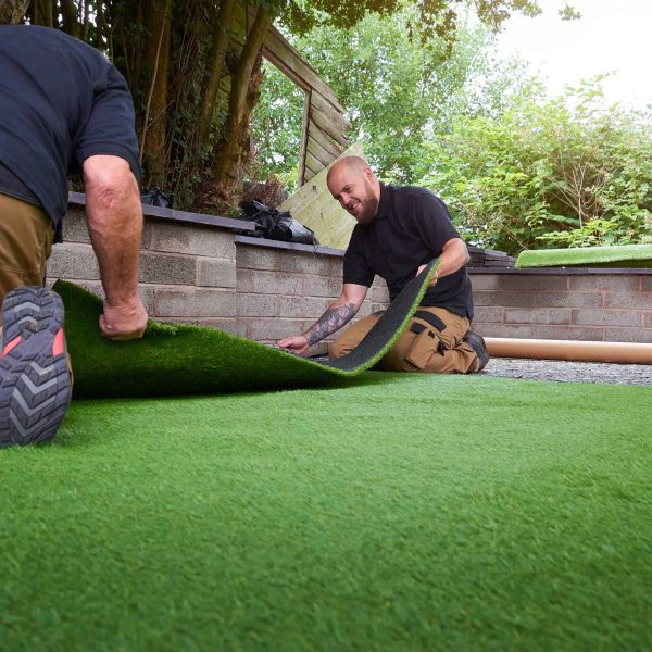 Professional artificial turf installation beside a tree as part of landscape design